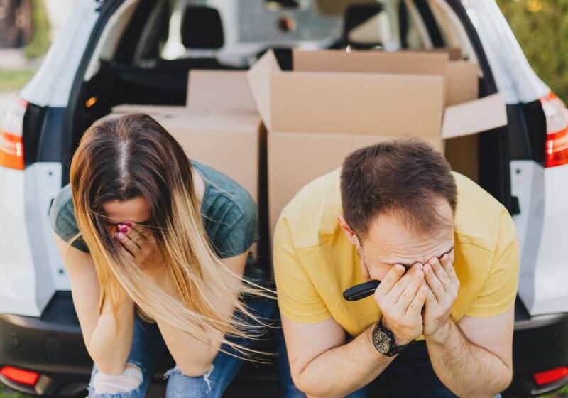 Couple looking upset sitting in their car after their house sale fell through